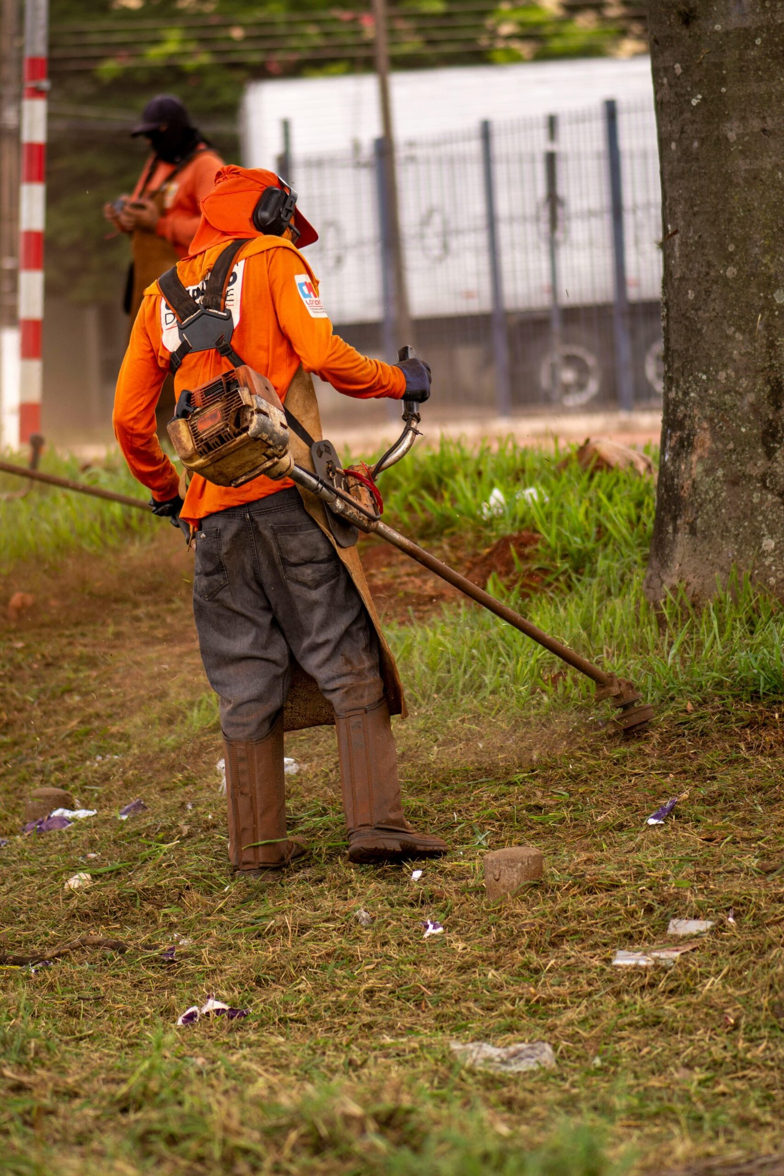 Man wearing protective gear using string trimmer outdoors.